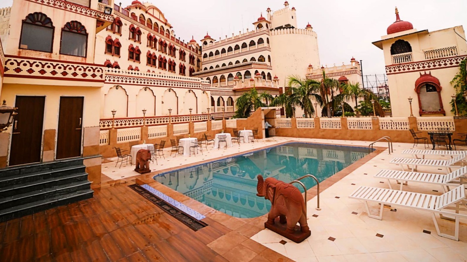 Rooftop swimming pool with heritage palace facade at Fort Chandragupt Hotel Jaipur